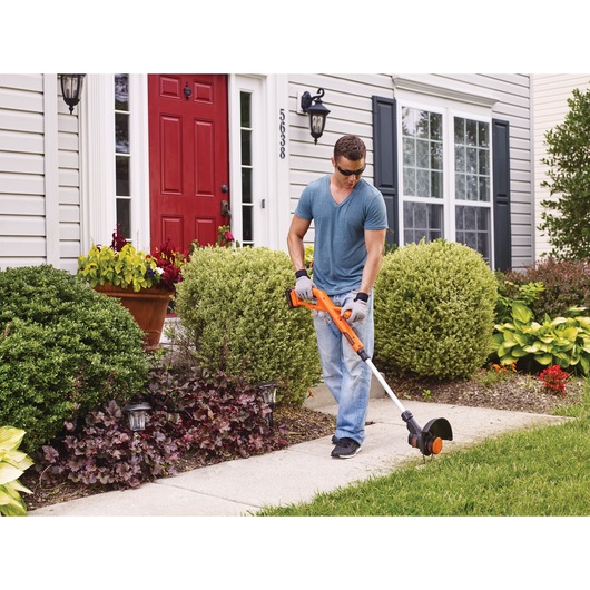 20 volt MAX lithium 10 inch string trimmer edger being used by a person to trim grass.